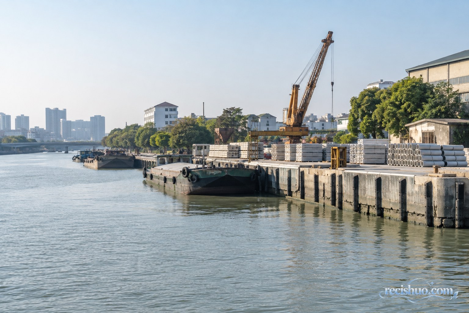 苏州城市运河岸边的小型货运泊位与整齐堆放的建材