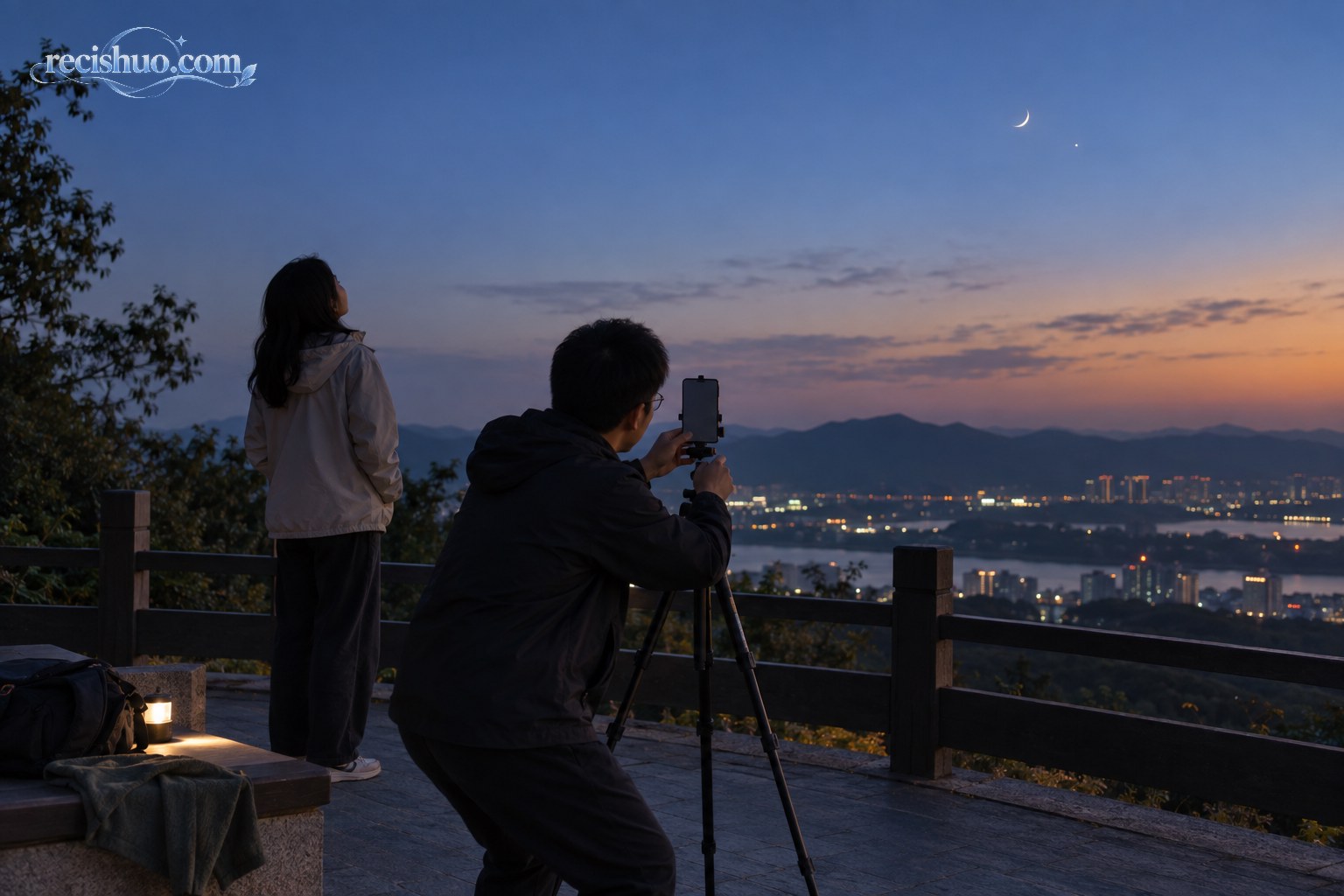 城市郊外观景平台上,两名观测者使用手机和三脚架拍摄金星伴月