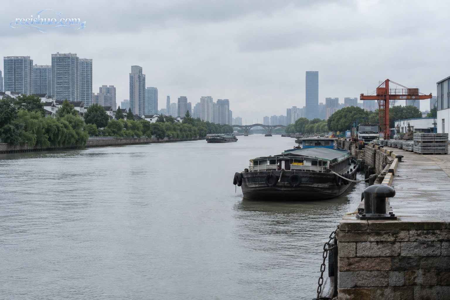 阴天自然光下的苏州城市运河、货船与沿岸码头设施