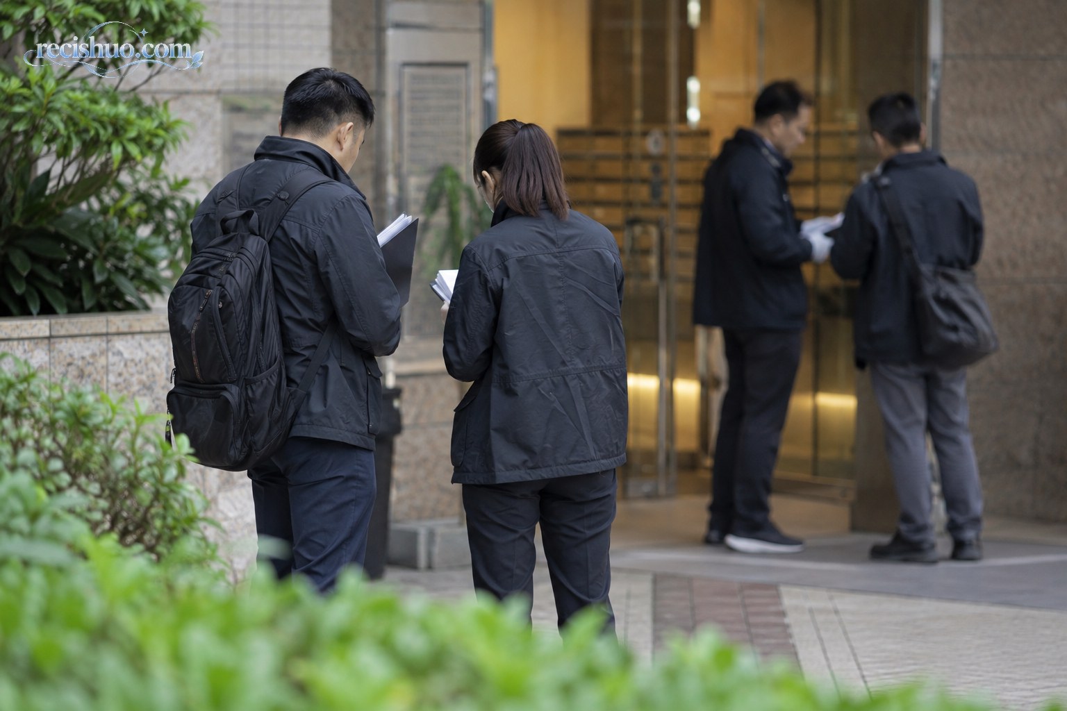 调查人员在住宅入口外核对资料并记录现场情况