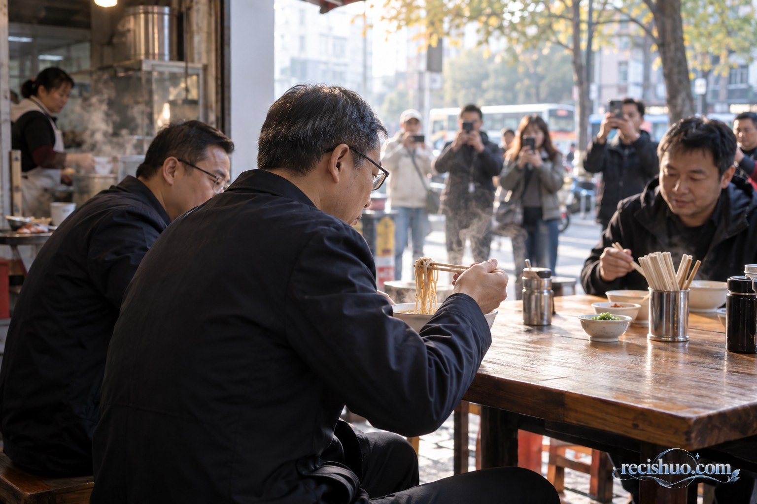 清晨早餐店内,一名中年男子与同事吃面,店外有市民用手机拍摄
