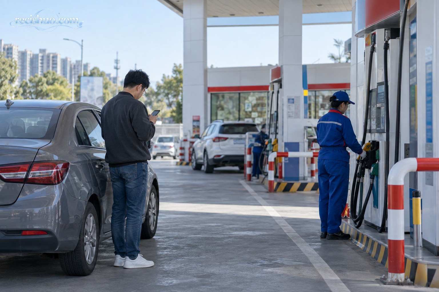 车主在城市加油站查看手机并等待车辆加油