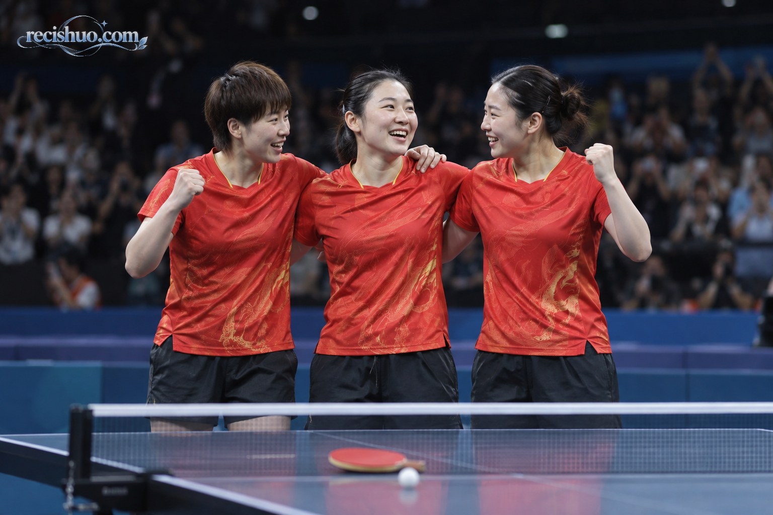 三名身穿红色运动服的中国女子乒乓球队员在球台旁并肩庆祝