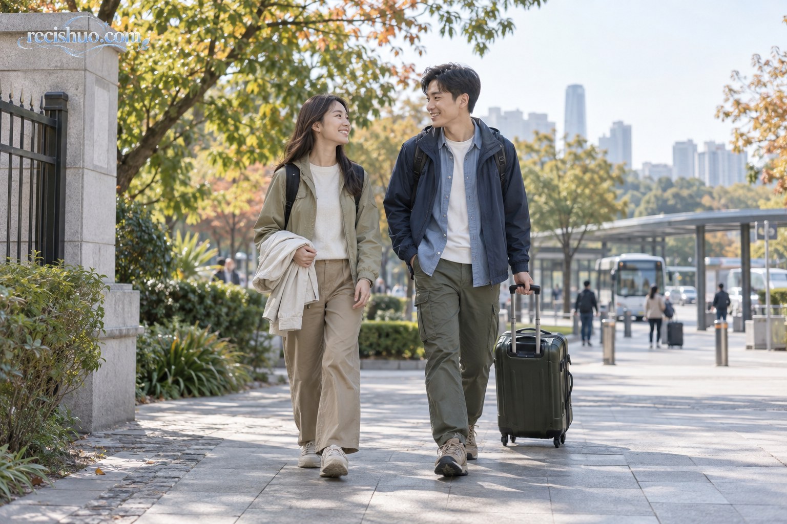 两名游客穿着轻便分层服装,在秋日城市公园附近拉着行李箱步行