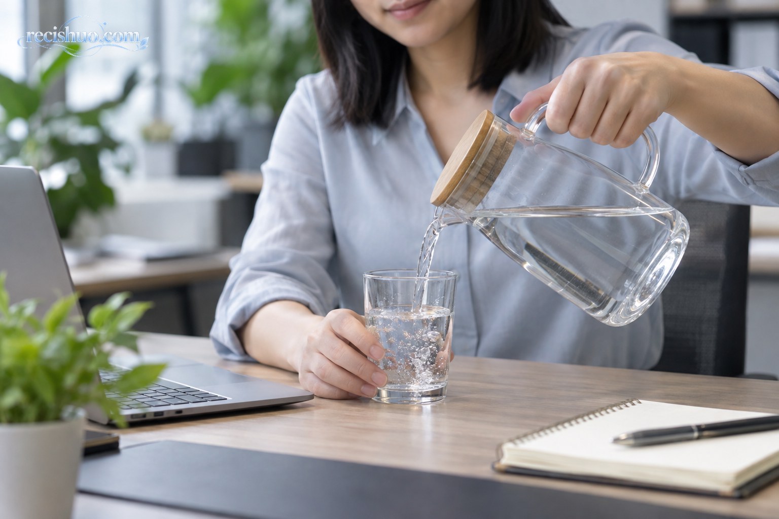 职场人士在办公桌旁用玻璃水壶向杯中倒水