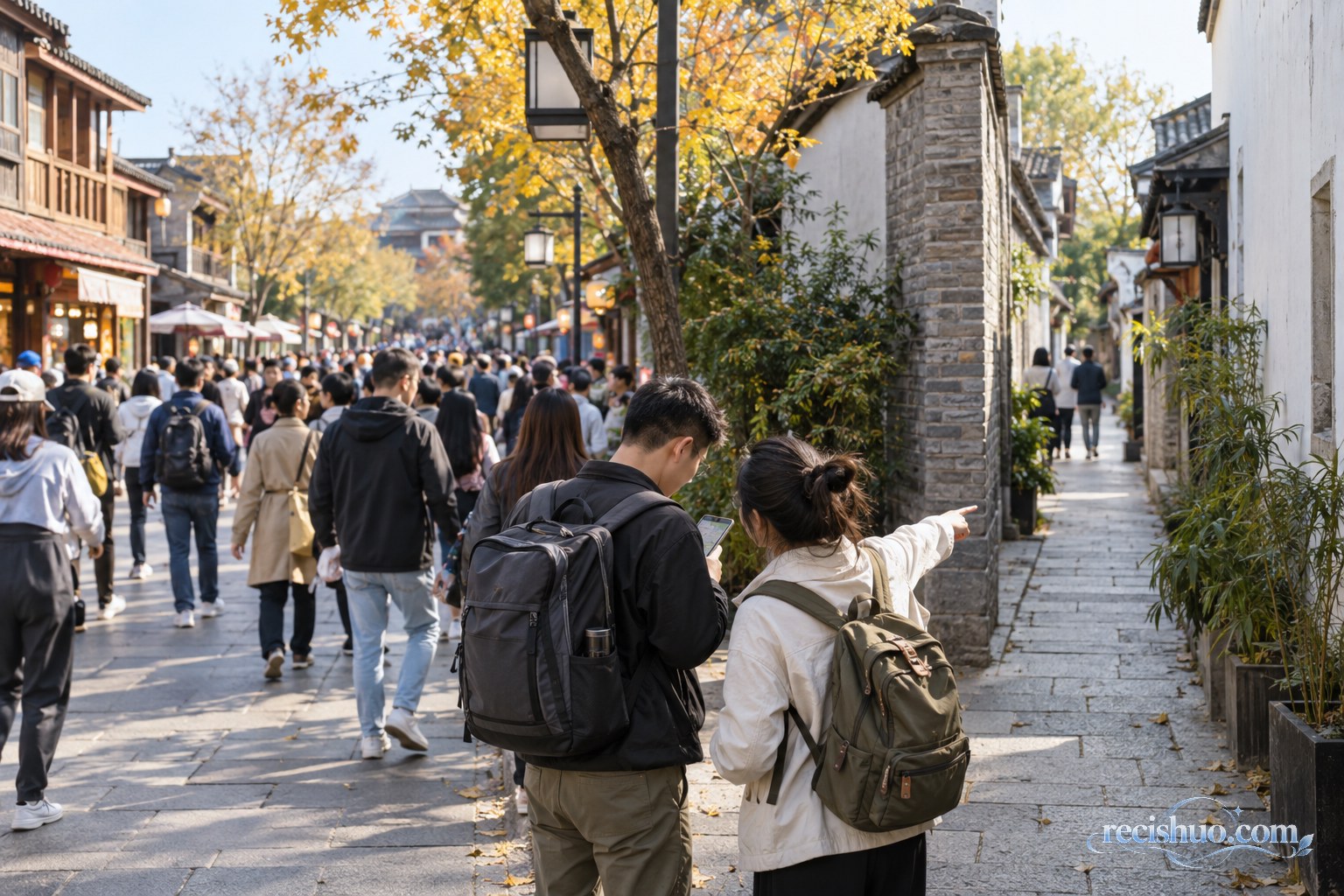 秋日傍晚的高铁站候车大厅内,两名携带行李的旅客查看手机行程,周围已有不少候车乘客