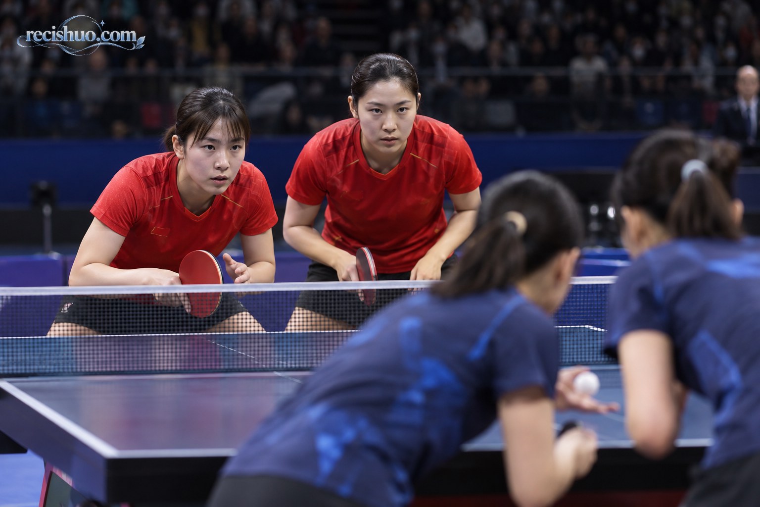 红蓝双方女子双打选手在乒乓球台两侧专注准备接发球