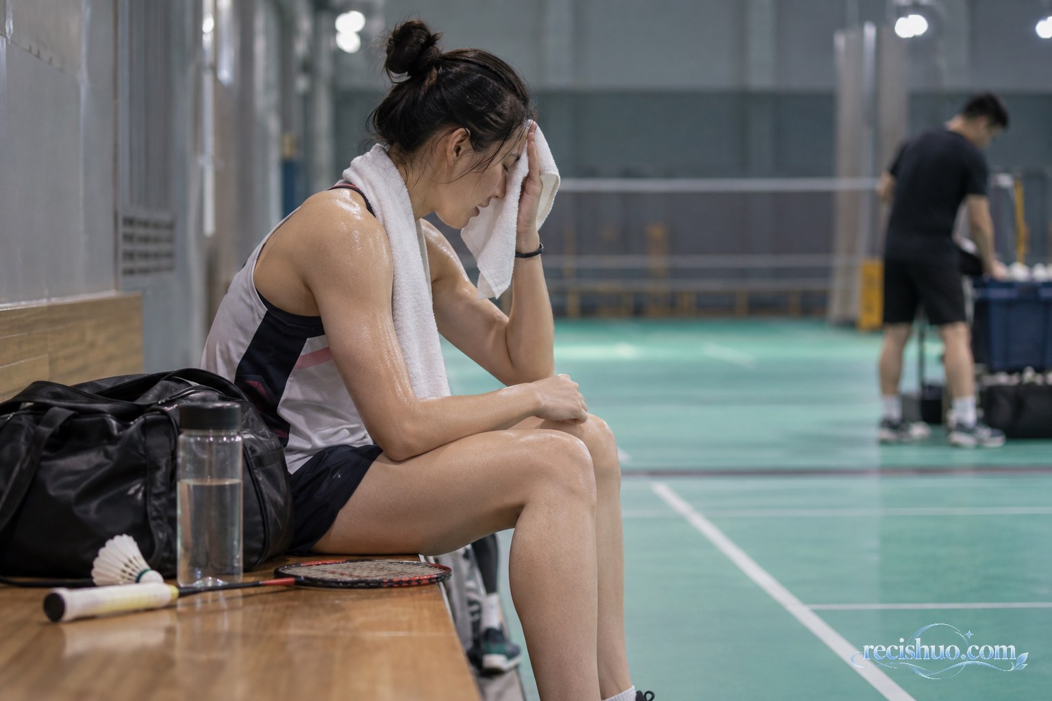 女子羽毛球运动员赛后坐在场边擦汗恢复体力