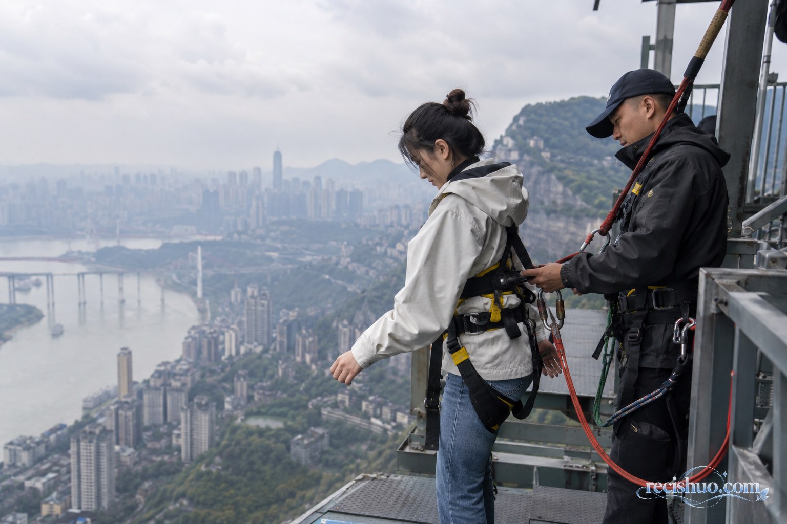 重庆山地景区高处平台上工作人员为游客检查安全绳和安全带