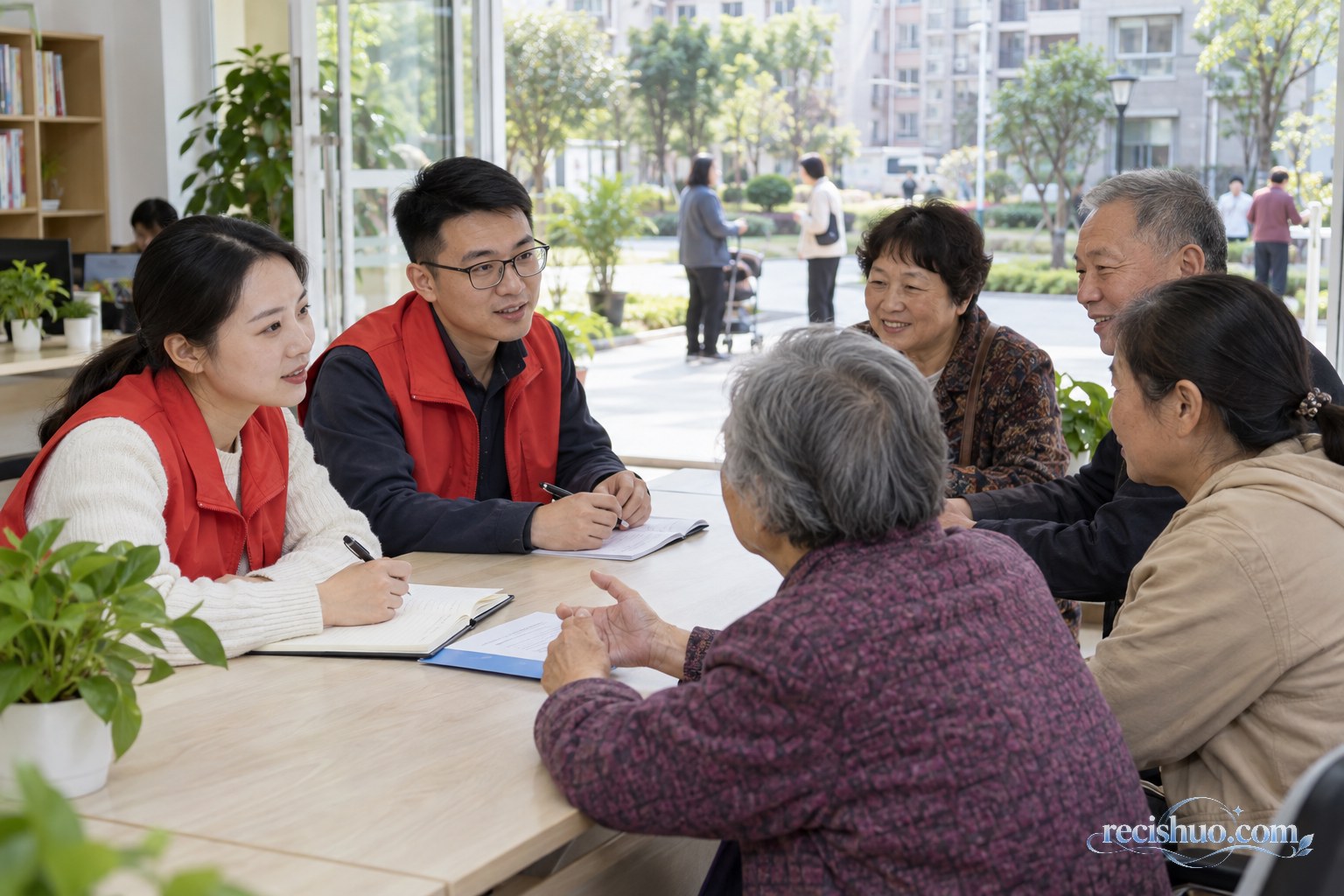 社区服务人员在明亮的服务大厅与居民围桌交流并记录诉求