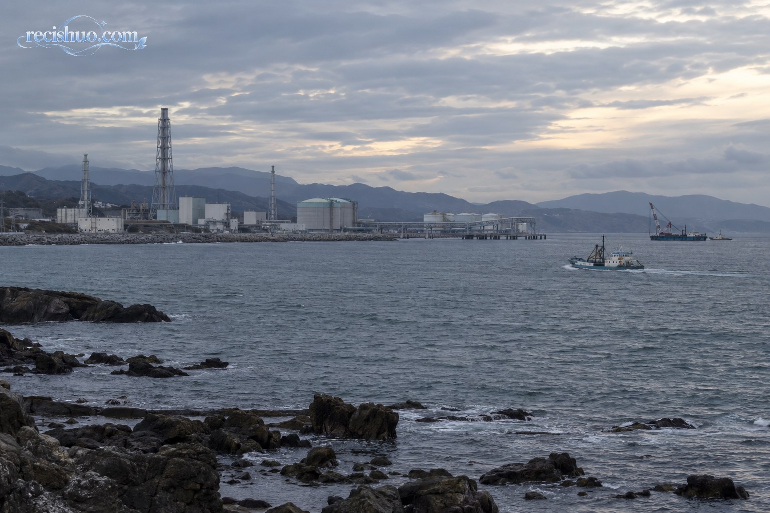 日本东北部海岸远处的临海工业设施与正在航行的作业船