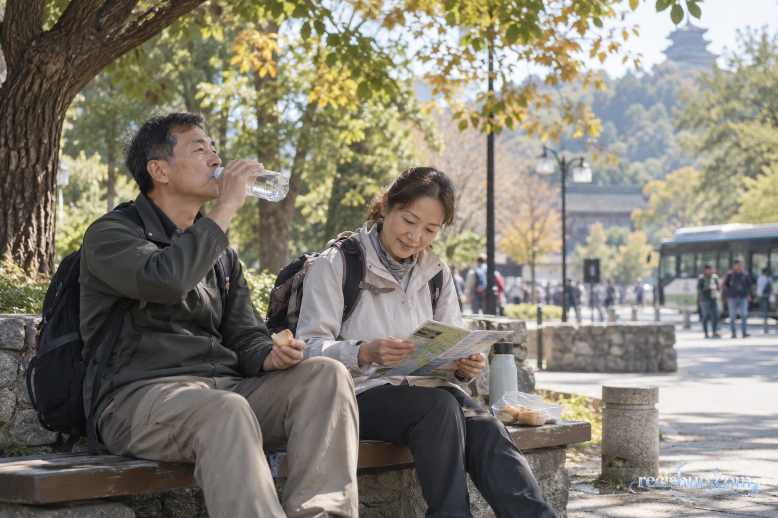 两位中年游客在公园树荫下喝水进食并查看路线