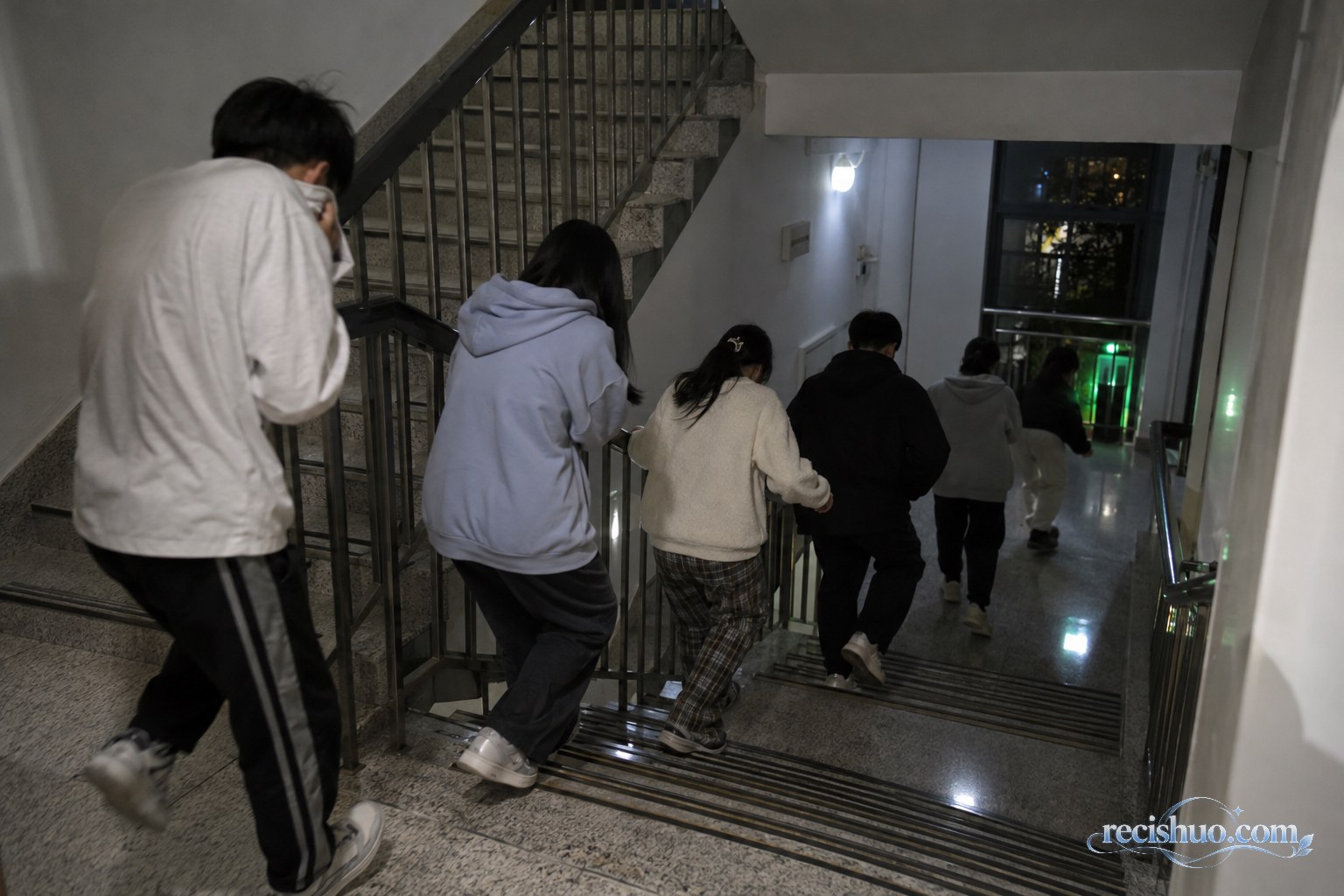 大学生夜间沿宿舍楼梯有序向下撤离的消防安全示意画面
