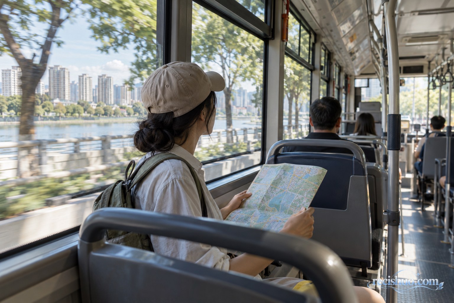 旅行者坐在城市公交车窗边查看地图并欣赏沿途河岸风景