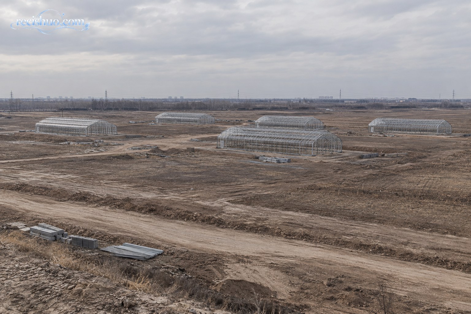 广阔农业项目用地上仅有五座未完工温室大棚的远景