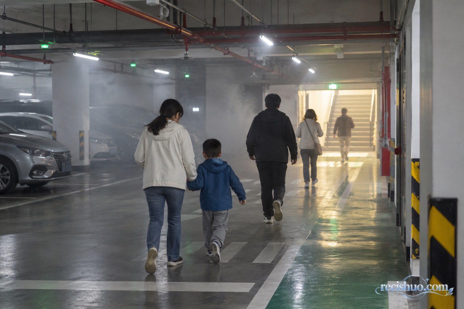 居民在出现烟雾的地下车库内沿安全出口有序撤离