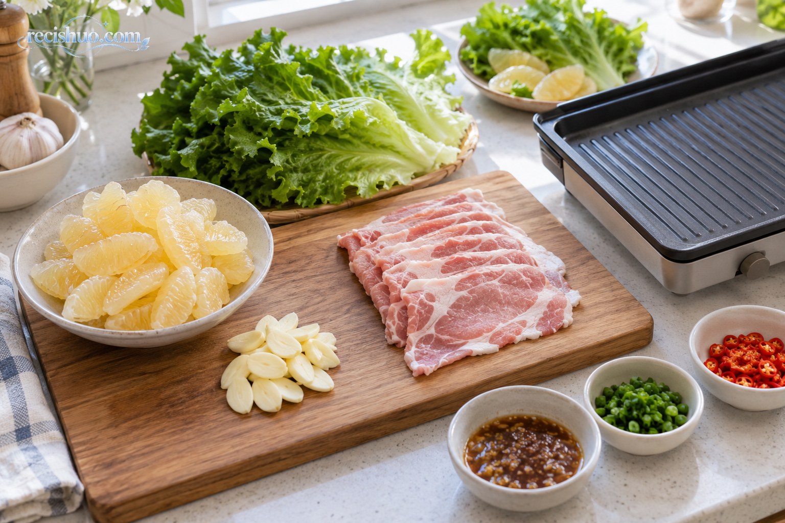 家庭厨房中分区摆放的柚子果肉、薄切猪肉、生菜和烤盘