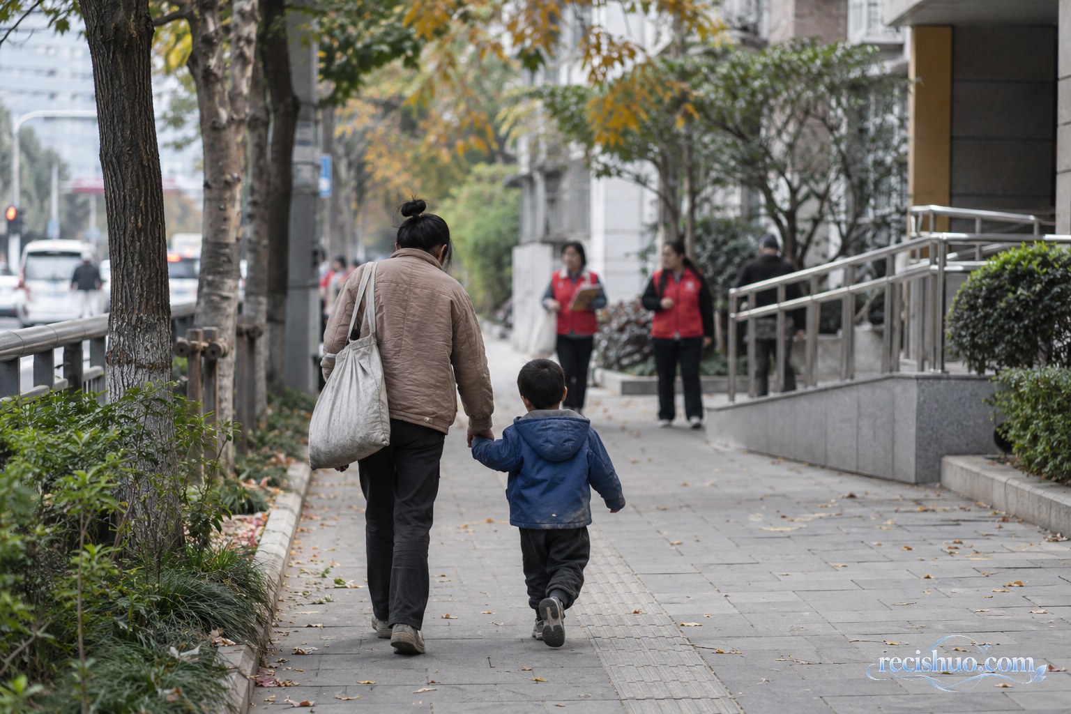 社区工作人员在服务站外为一名女子和幼童递上保暖衣物与饮用水