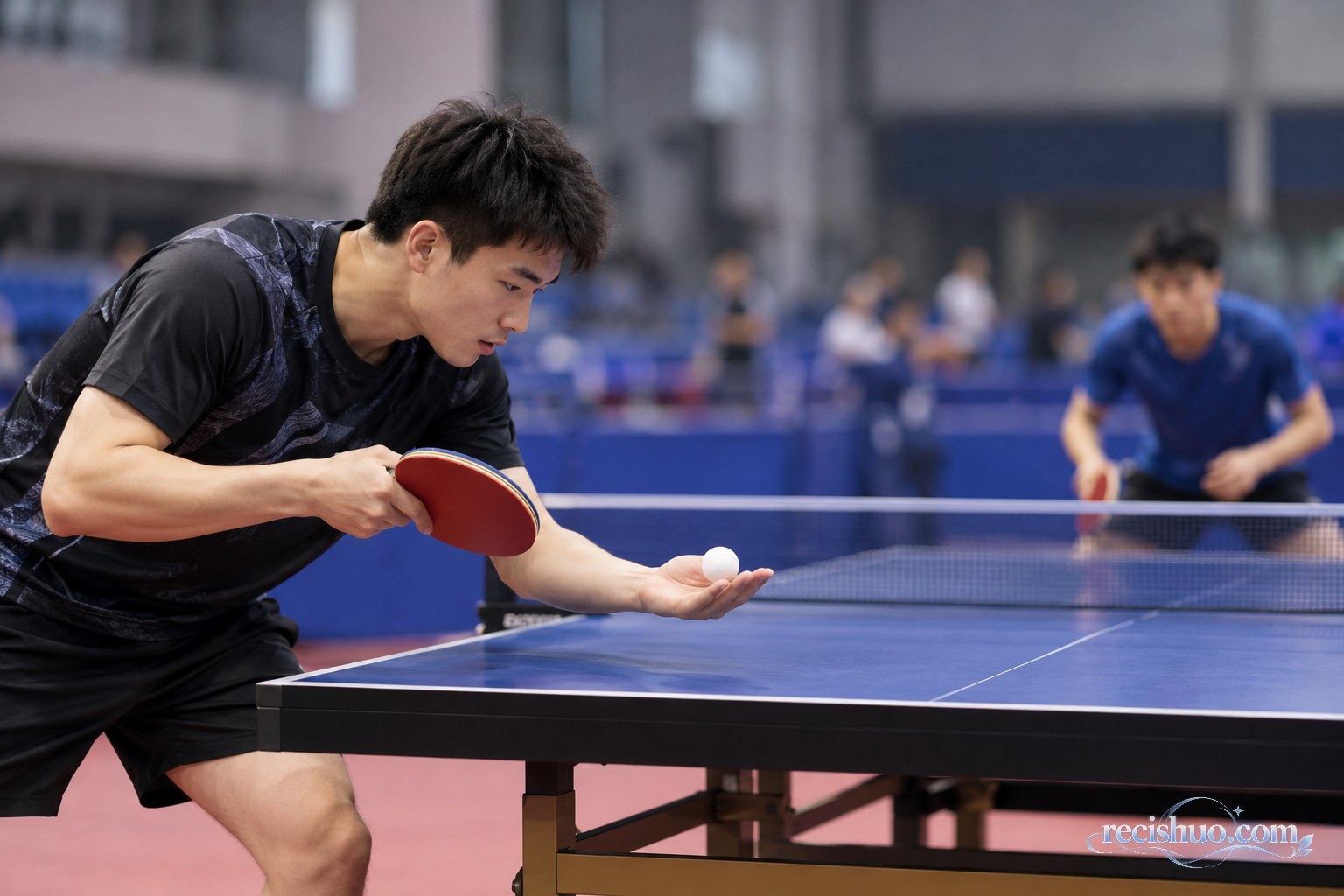 乒乓球训练馆内一名男子运动员在球台前准备发球