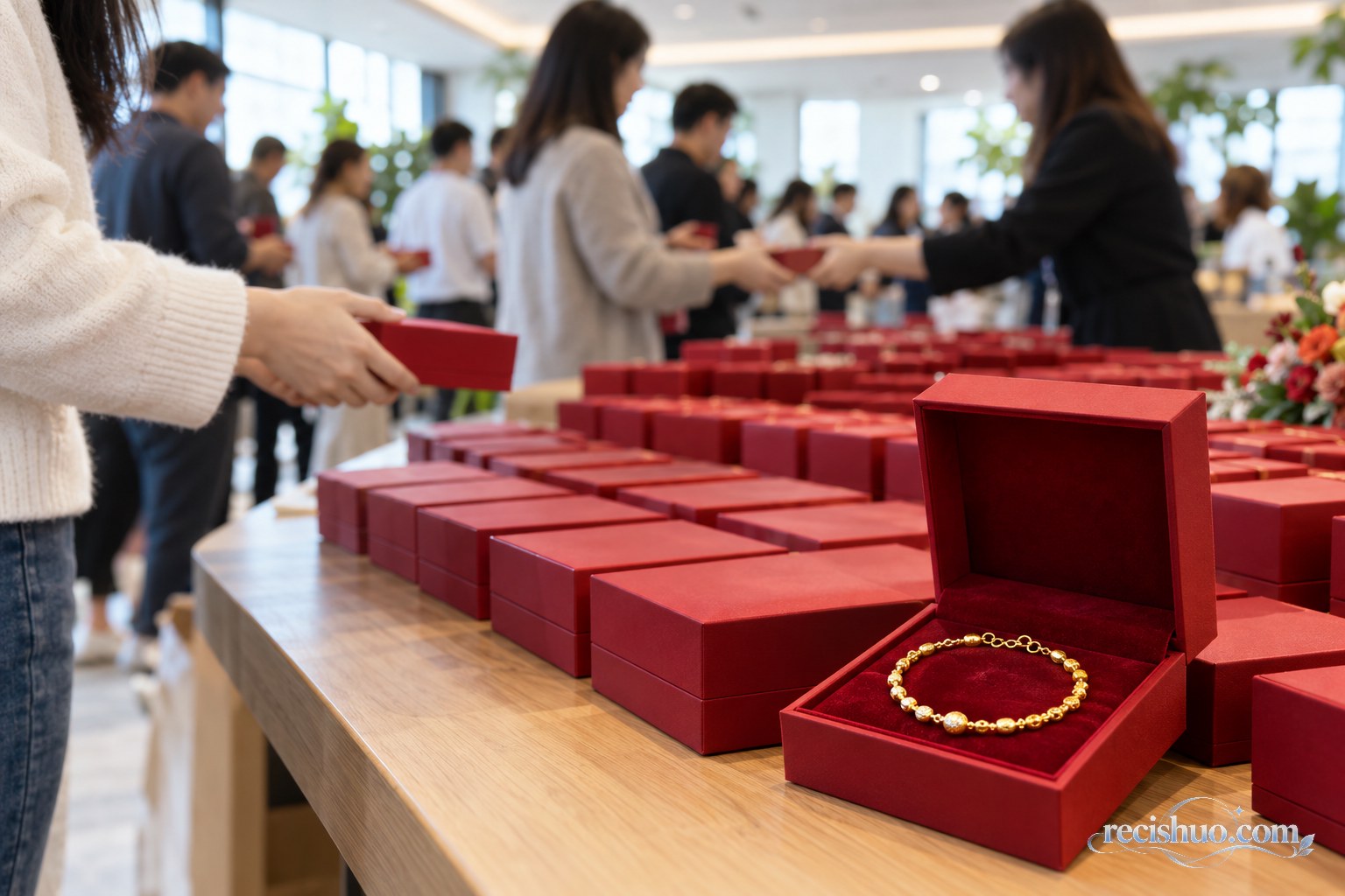 公司活动空间内整齐摆放红色首饰盒,员工有序领取纯金纪念手链