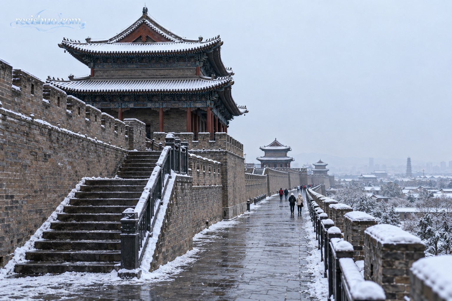 薄雪勾勒大同古城墙与城楼轮廓，石阶和步道路面仍显湿滑