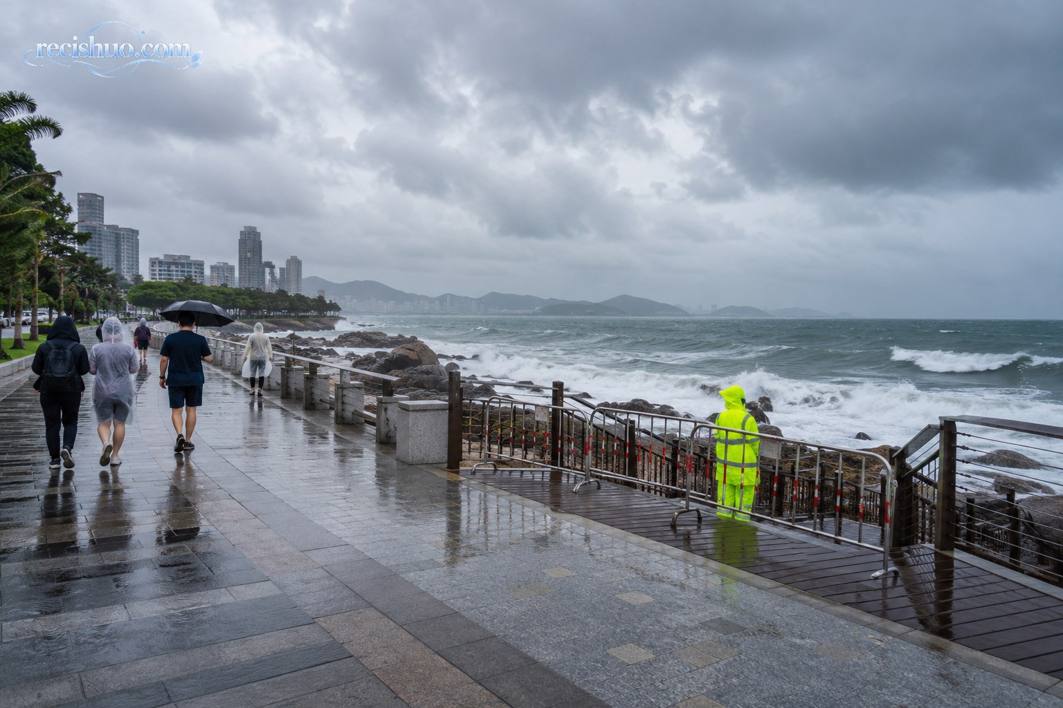 风雨中的沿海步道入口被护栏封闭，工作人员正在巡查