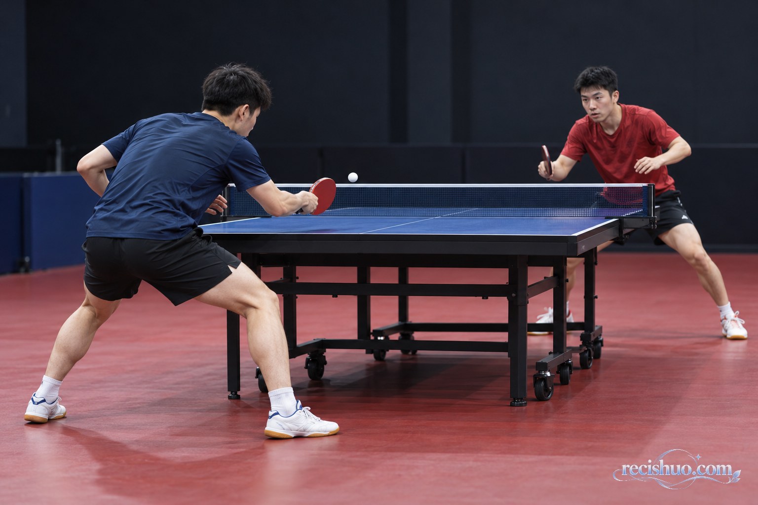 两名男子乒乓球运动员在训练场进行近台攻防的侧面画面