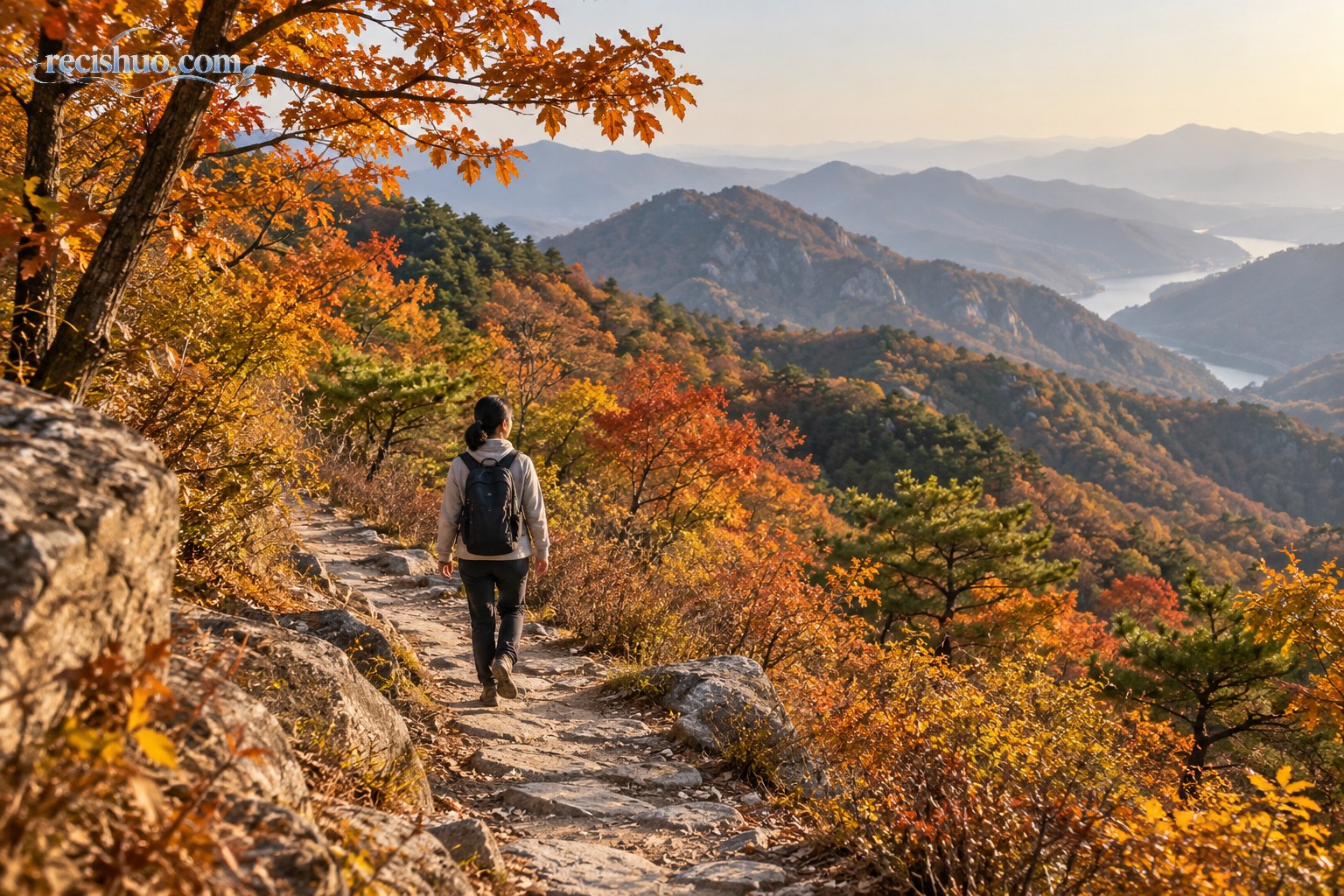 一名徒步者沿着铺满秋色的山间步道走向远处群山