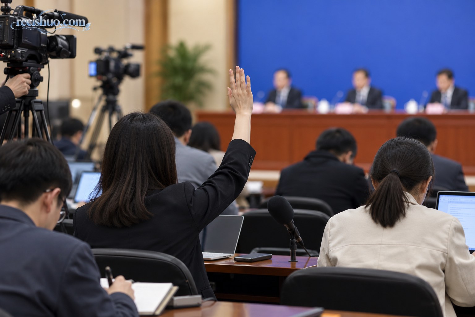 新闻发布会上记者举手提问并记录信息的现场