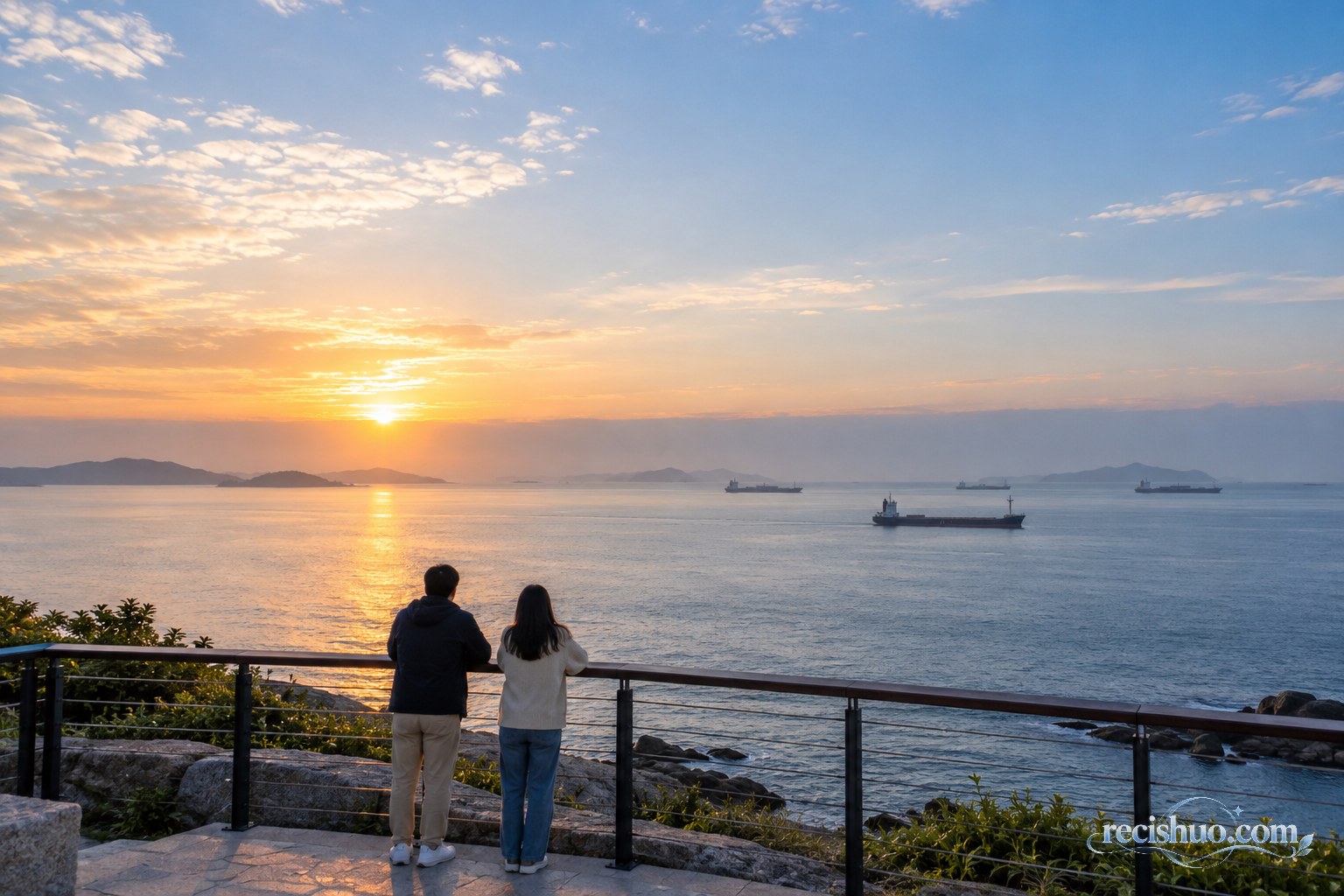 两名市民在海边平台远望平静海面和往来民用货轮