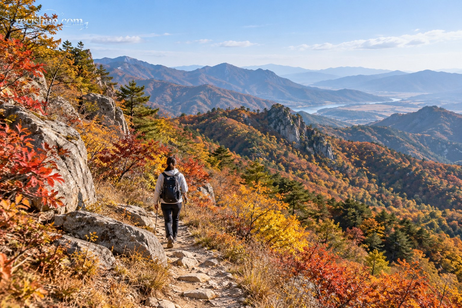 徒步者沿秋色山间步道行走,远处可见层叠山脊与林海