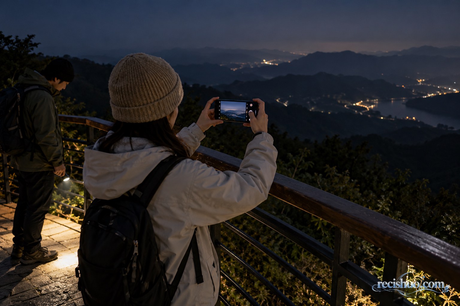 两名游客在有护栏的观景台安全拍摄远山夜景