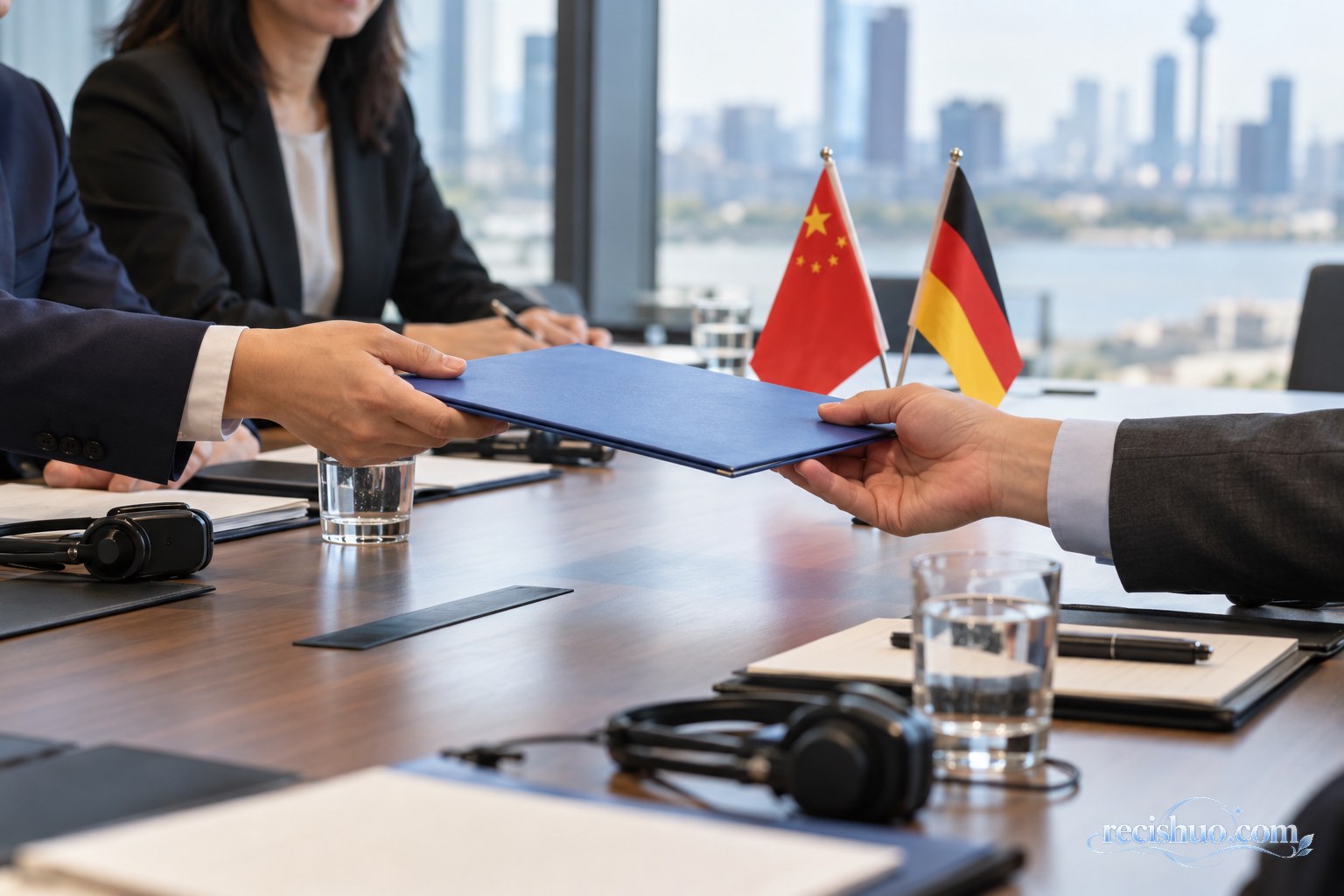 中德双方代表在会议桌前交换文件，桌上摆放两国国旗与翻译设备