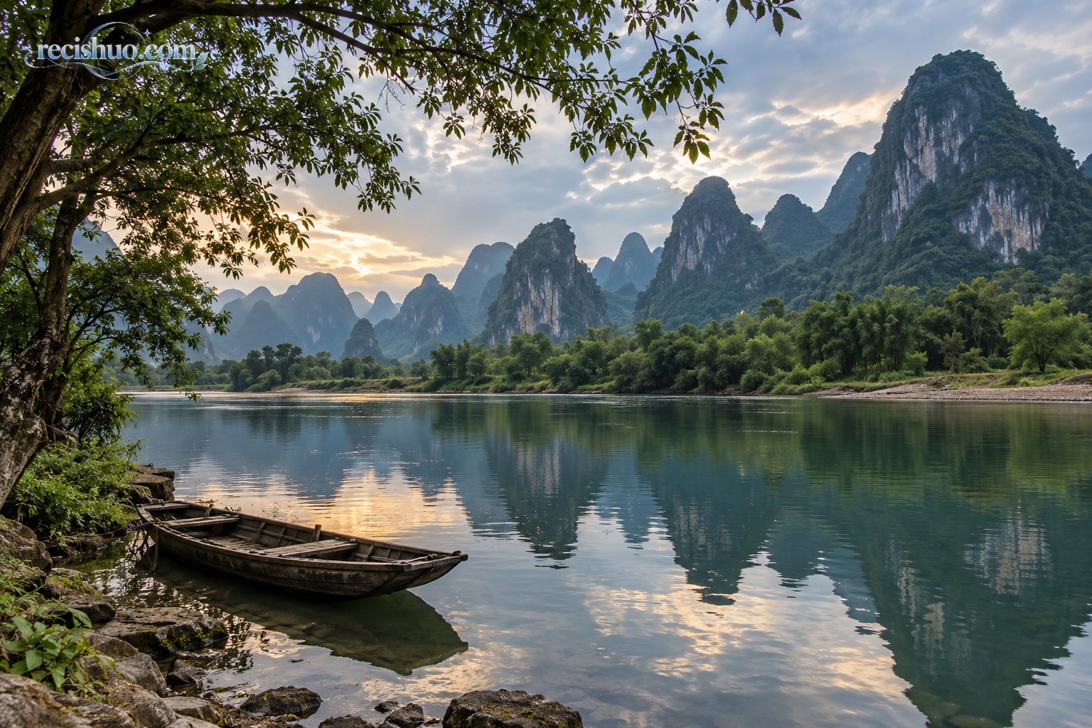 阳朔临水峰林在傍晚柔光下形成倒影,岸边停着一艘小木船
